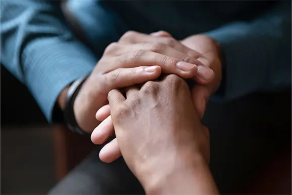 A close up of an attorney from Van Law Firm holding hands with a client and offering comfort after a personal injury. 