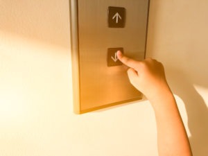 Child pushing the “down” button on an elevator.
