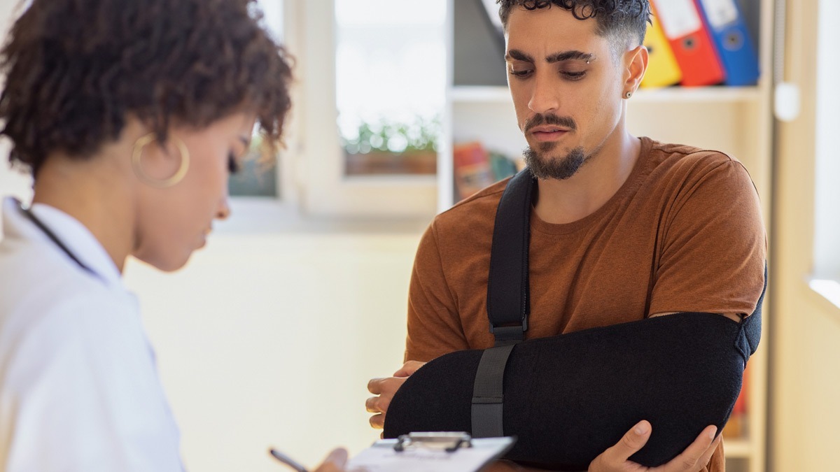 Man-with-arm-in-sling-talking-to-doctor