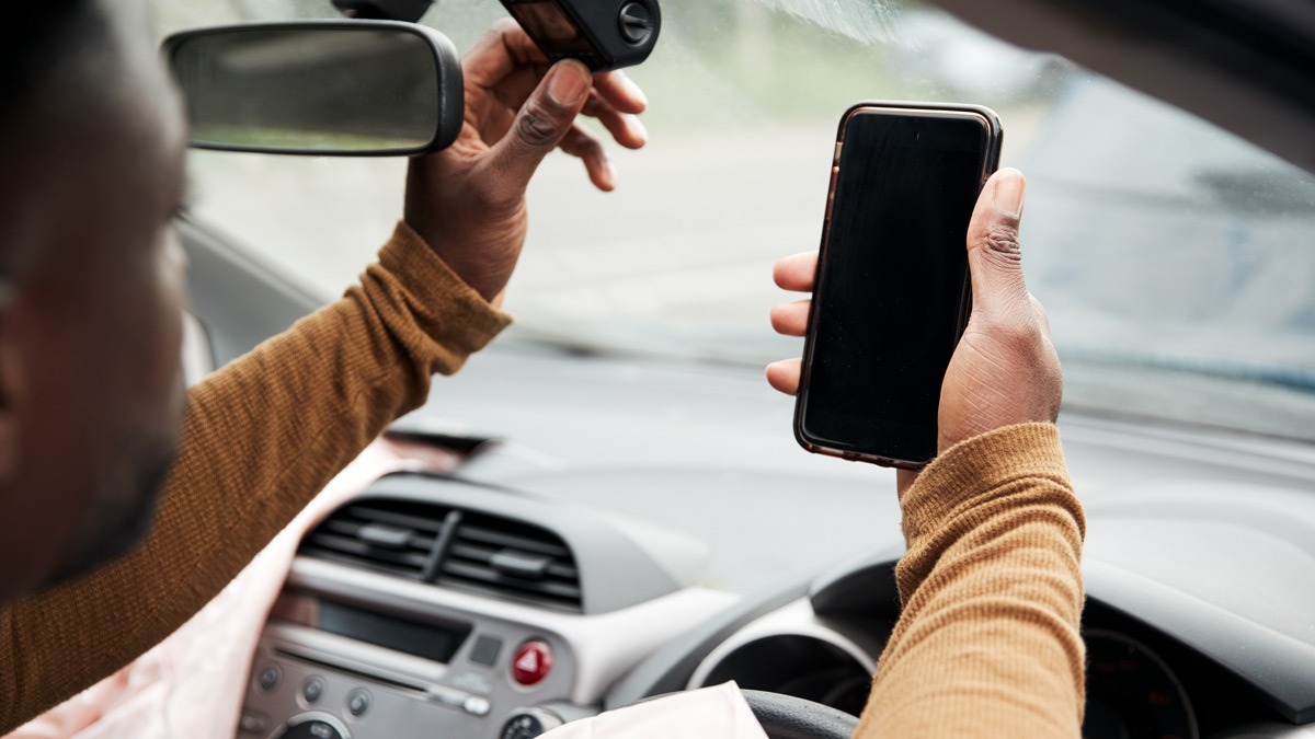 driver-using-phone-and-adjusting-dashcam