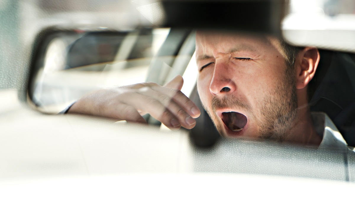 man-yawning-in-rearview-mirror