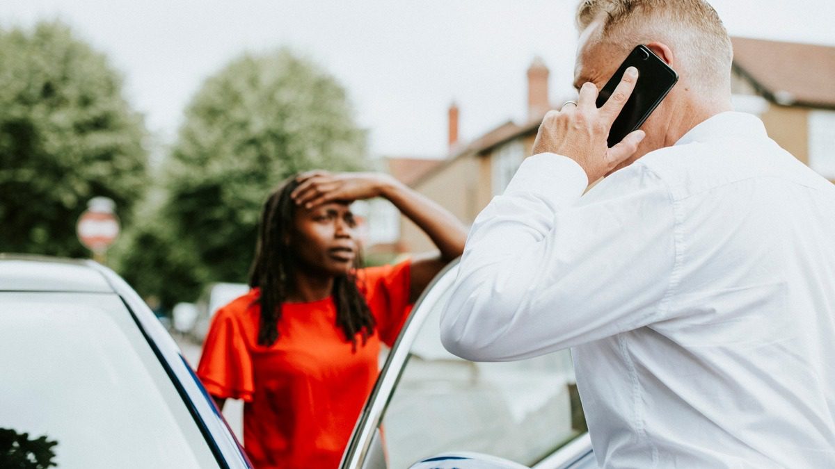 man-on-the-phone-after-a-car-accident-with-woman-in-background