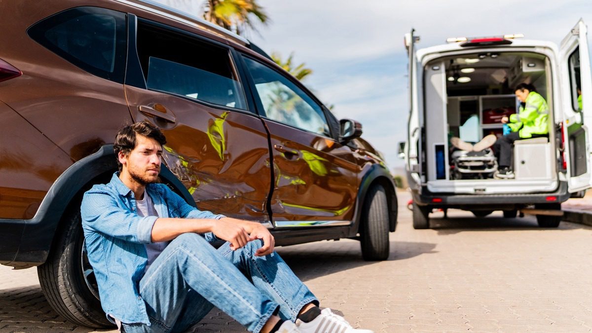 man-sitting-outside-of-his-car-after-an-accident