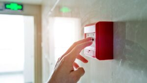 person-pressing-fire-alarm-in-hallway
