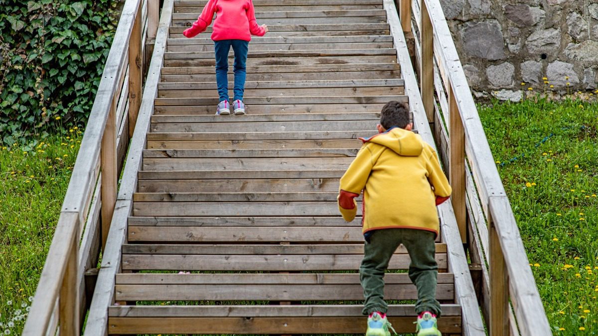 two-children-walking-up-wooden-steps-outdoors