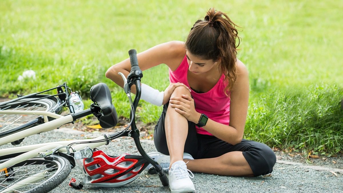 woman-examining-knee-after-falling-off-bike