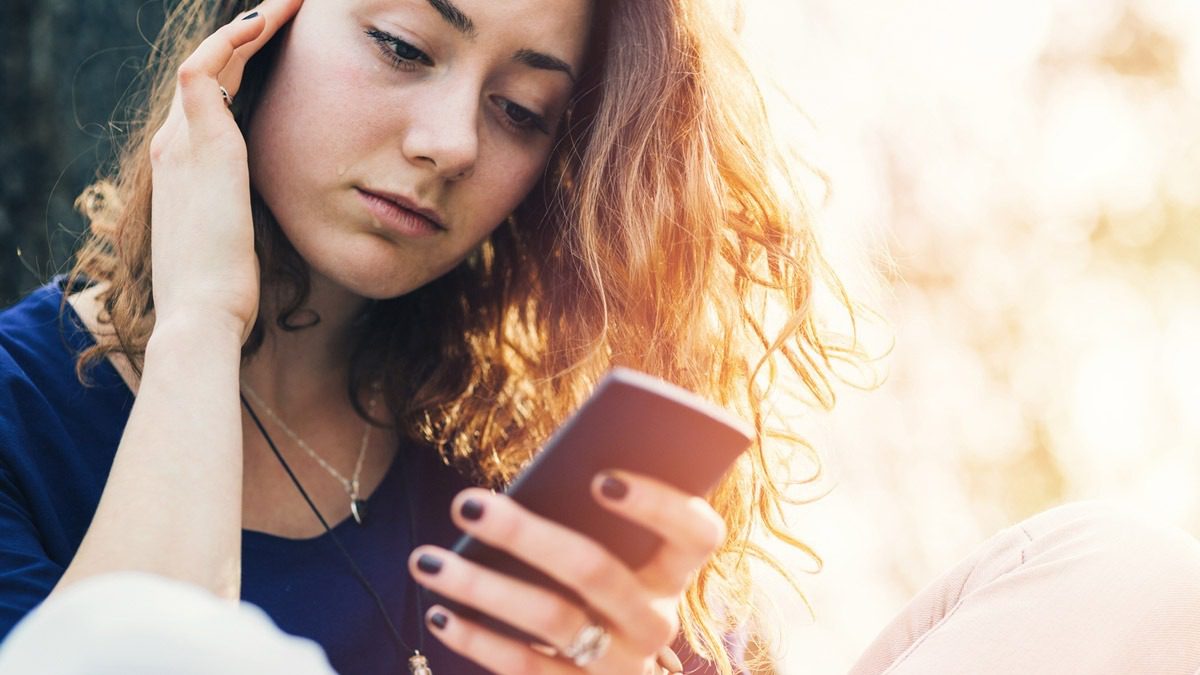 woman-sitting-outside-and-looking-at-phone
