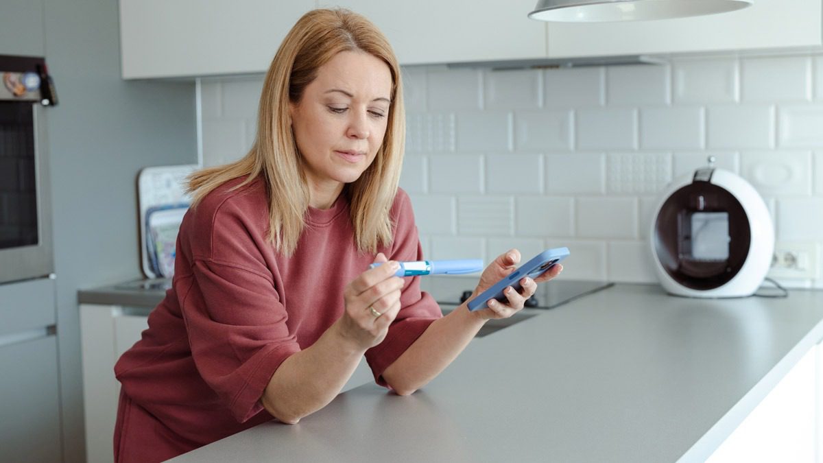 woman-in-kitchen-looking-at-GLP-1-pen