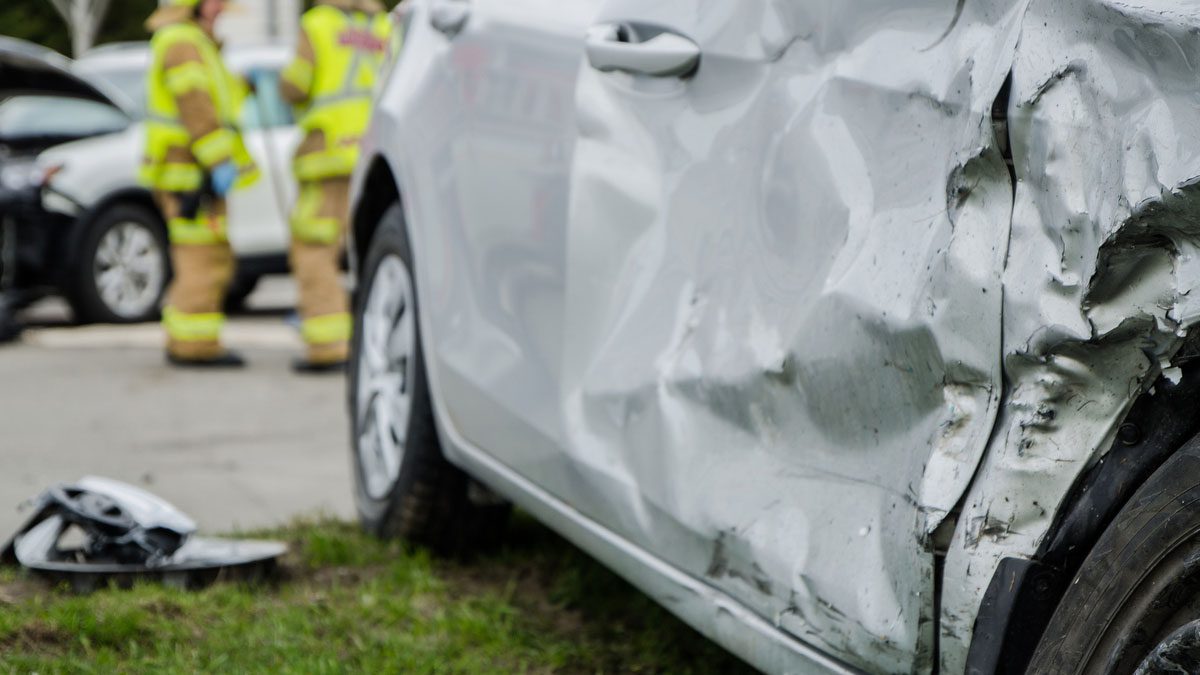 Close up on a car crash with two firemen in background