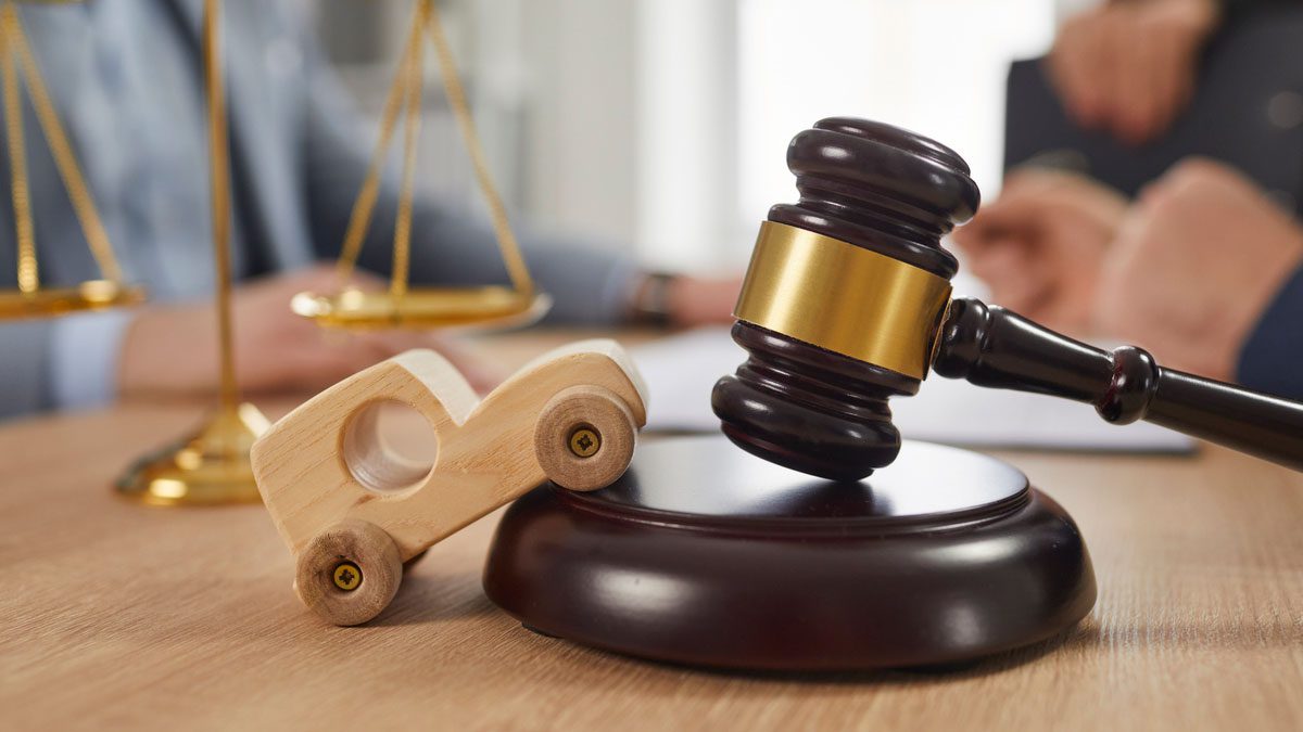 Toy car, gavel and scales of justice on table