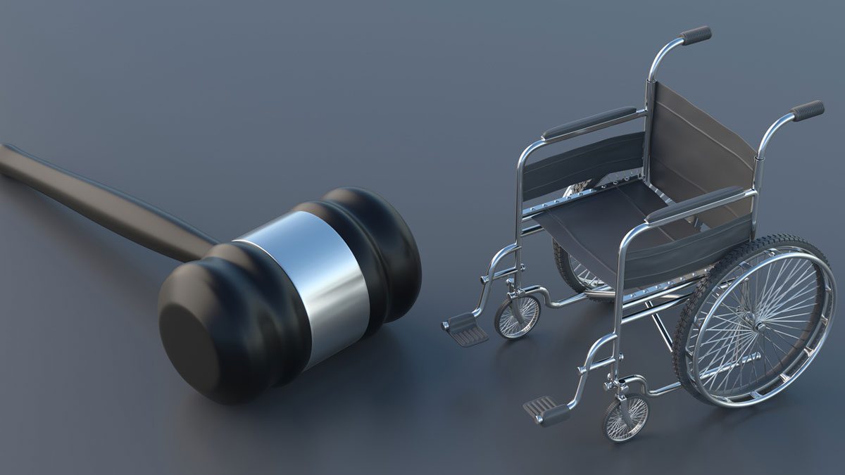 Wheelchair and judge gavel on gray background