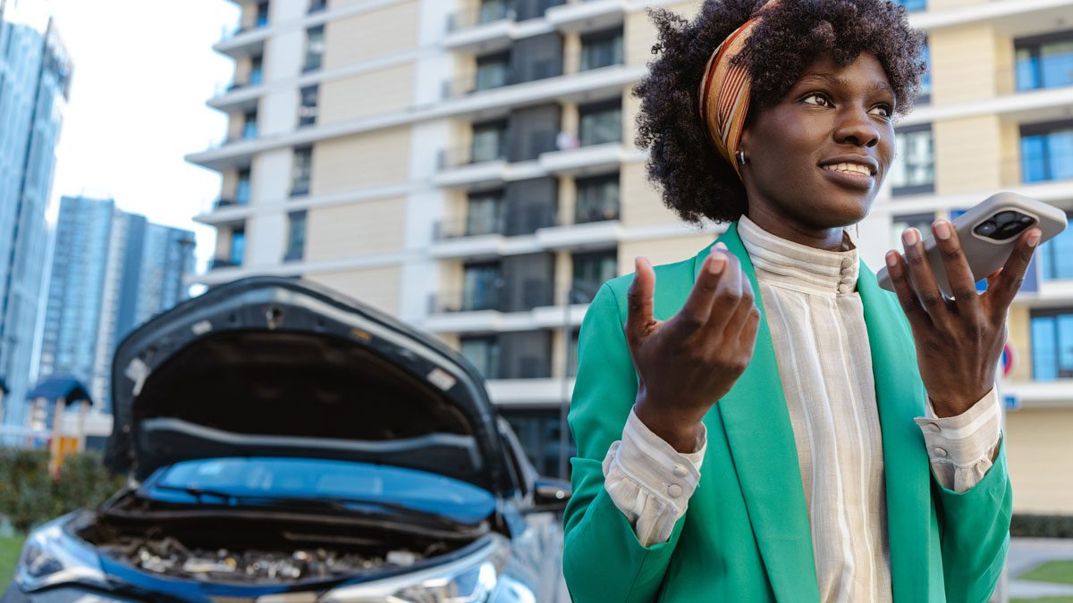 Woman-making-a-phone-call-next-to-a-car-with-a-raised-hood