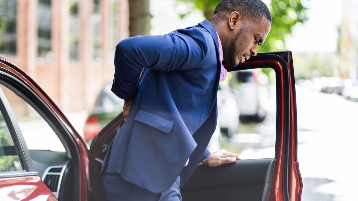 man with back pain exiting car