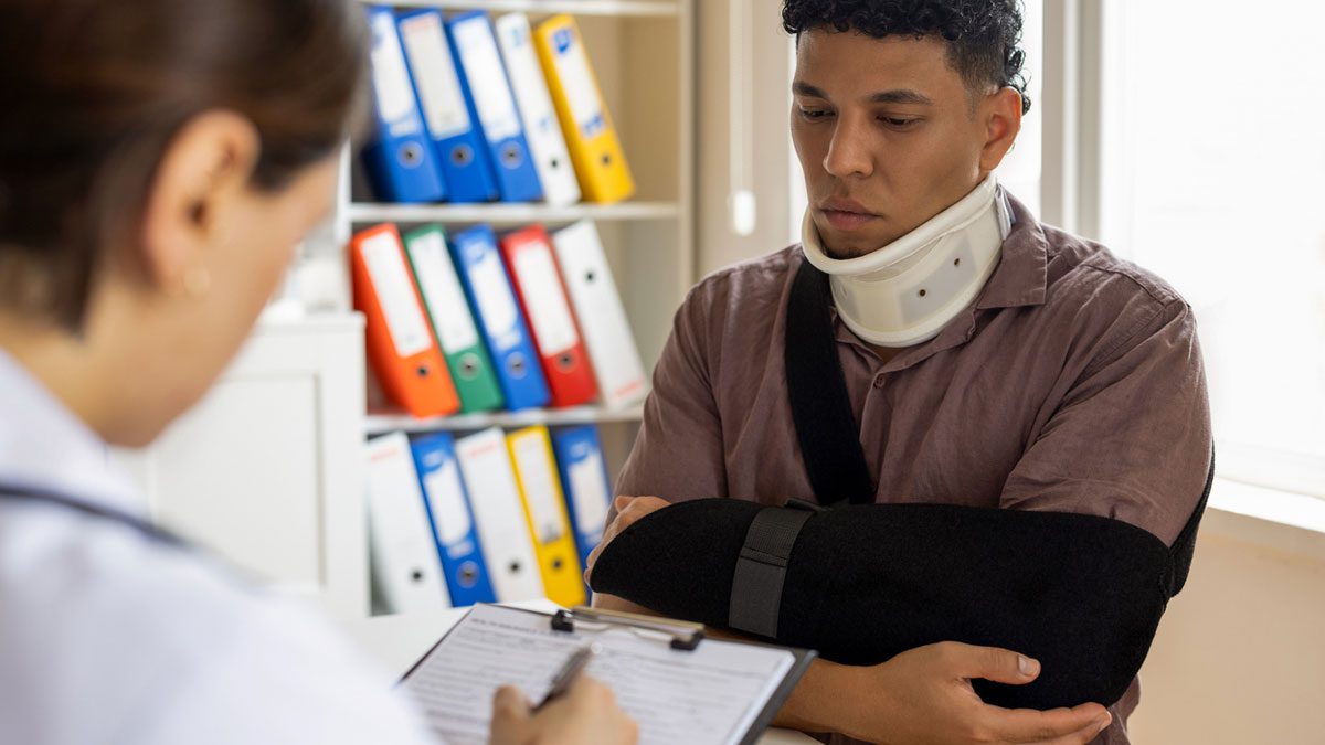 man-with-neck-brace-and-arm-sling-giving-information-to-doctor