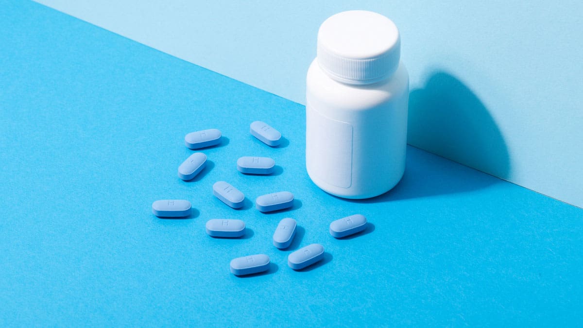 blue-pills-with-white-bottle-on-blue-surface