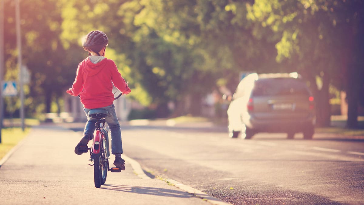boy-with-helmet-riding-bike-through-neighborhood