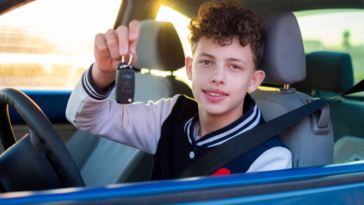 newly-licensed-driver-smiling-and-holding-keys-in-drivers-seat