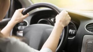 view-over-the-shoulder-of-teens-hands-on-steering-wheel