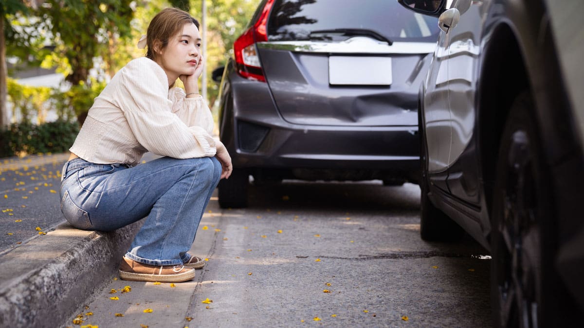 woman-sitting-on-curb-after-car-accident