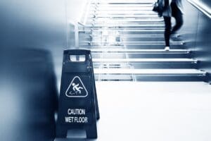 individual-walking-down-a-flight-of-stairs-with-a-wet-floor-sign-at-the-bottom