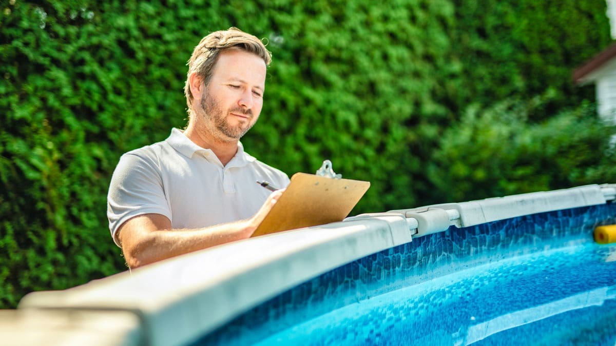 inspector-standing-next-to-above-ground-pool-with-clipboard