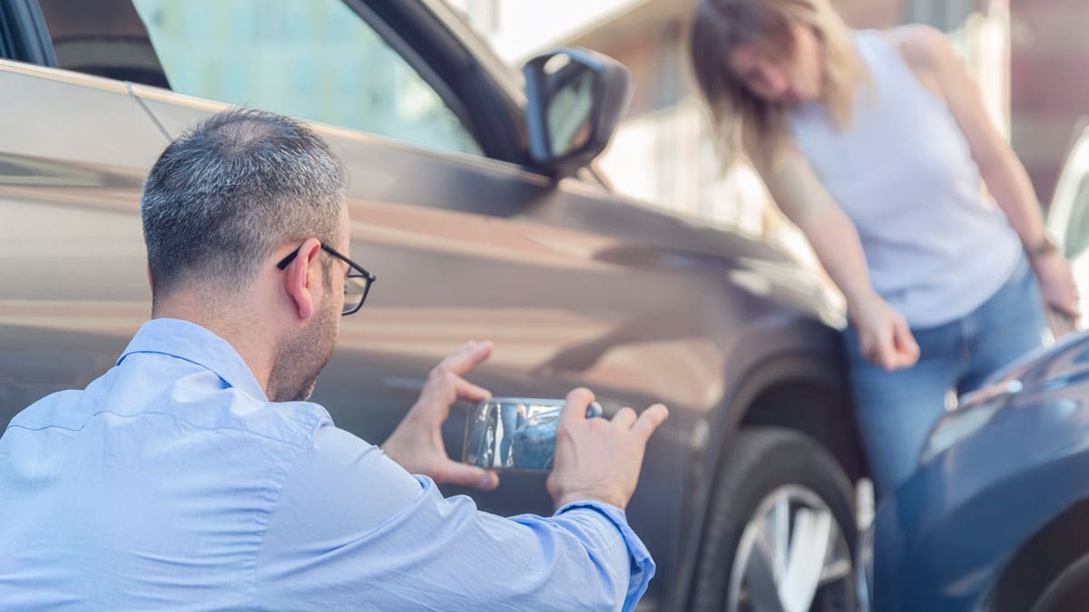 adjuster-photographing-damage-on-a-car-while-the-owner-waits