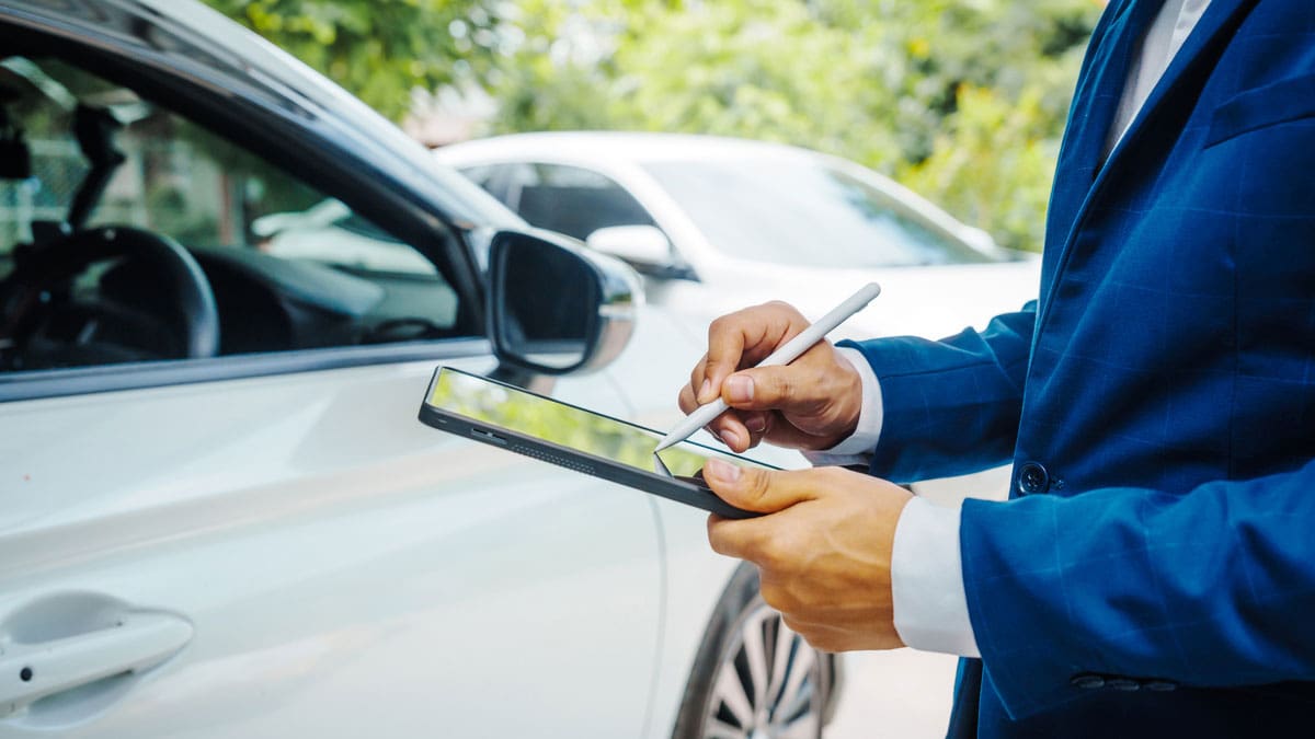 adjuster-using-a-tablet-beside-a-damaged-white-car