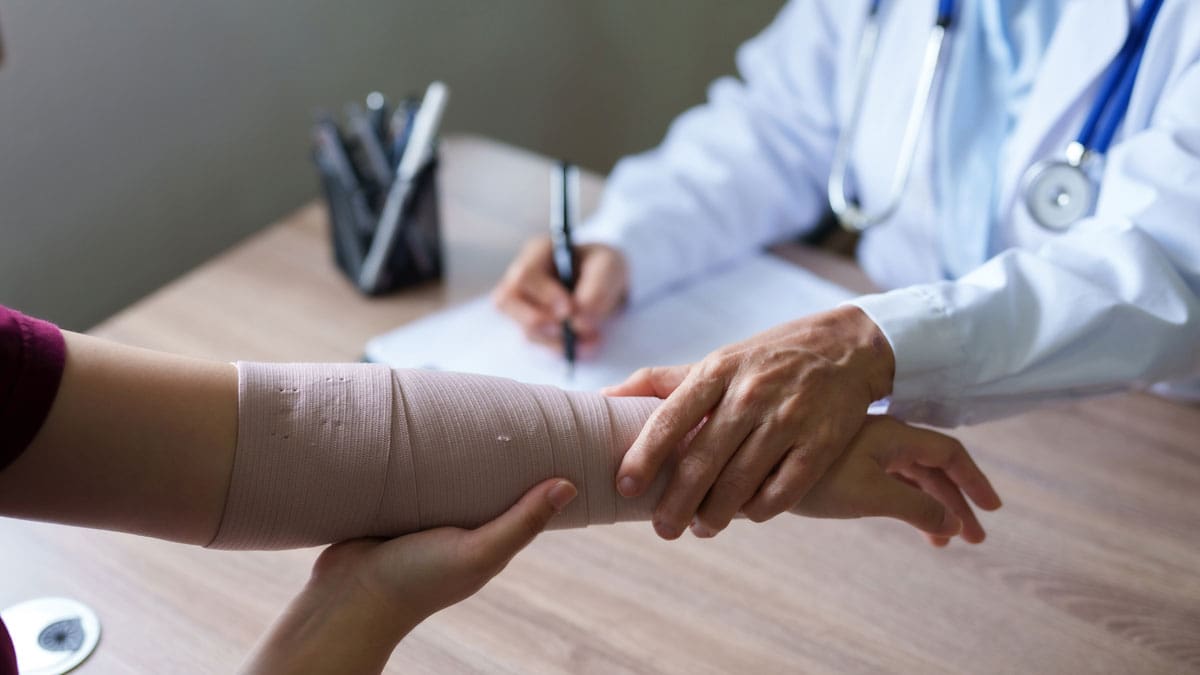 doctor-examining-a-patients-arm-while-taking-notes