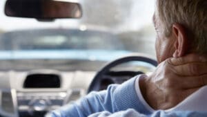 driver-holding-his-neck-behind-the-wheel-after-a-crash