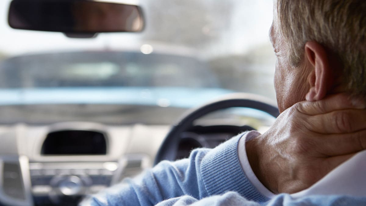driver-holding-his-neck-behind-the-wheel-after-a-crash