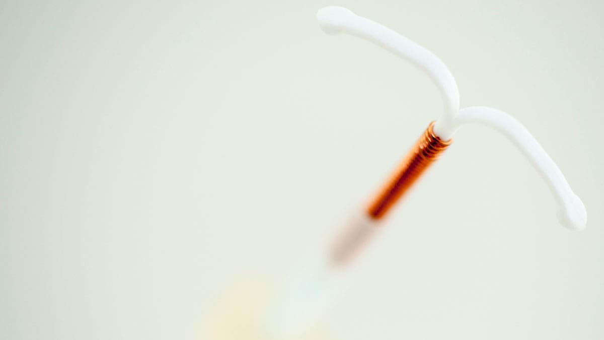 intrauterine-device-beside-an-inserter-on-a-plain-background