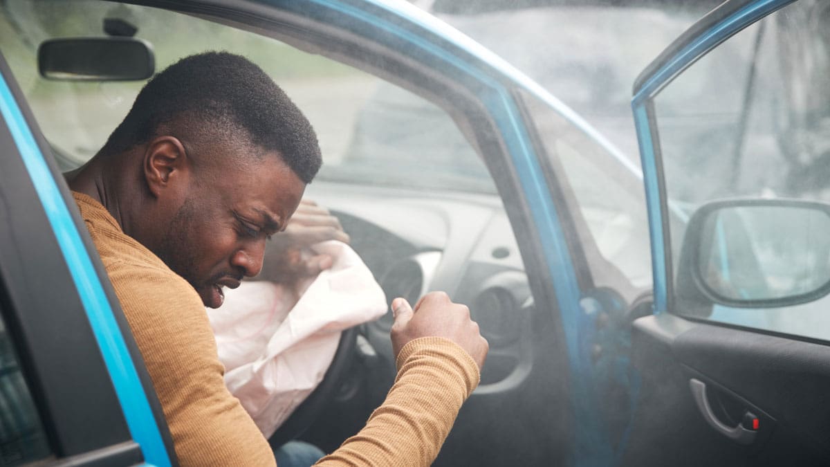 man-leaning-on-a-car-door-holding-his-head-after-a-collision