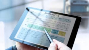 person-filling-out-an-daily-log-form-on-a-tablet-near-a-truck