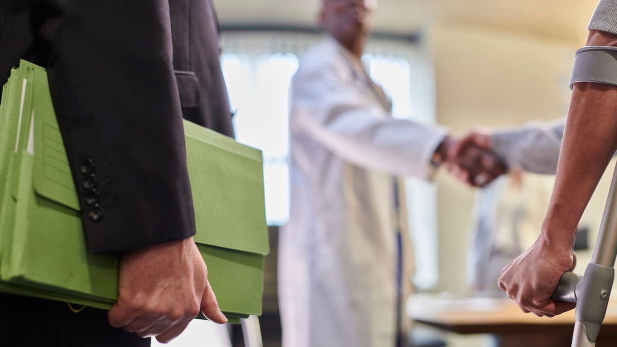 person-on-crutches-shaking-hands-with-someone-in-an-office