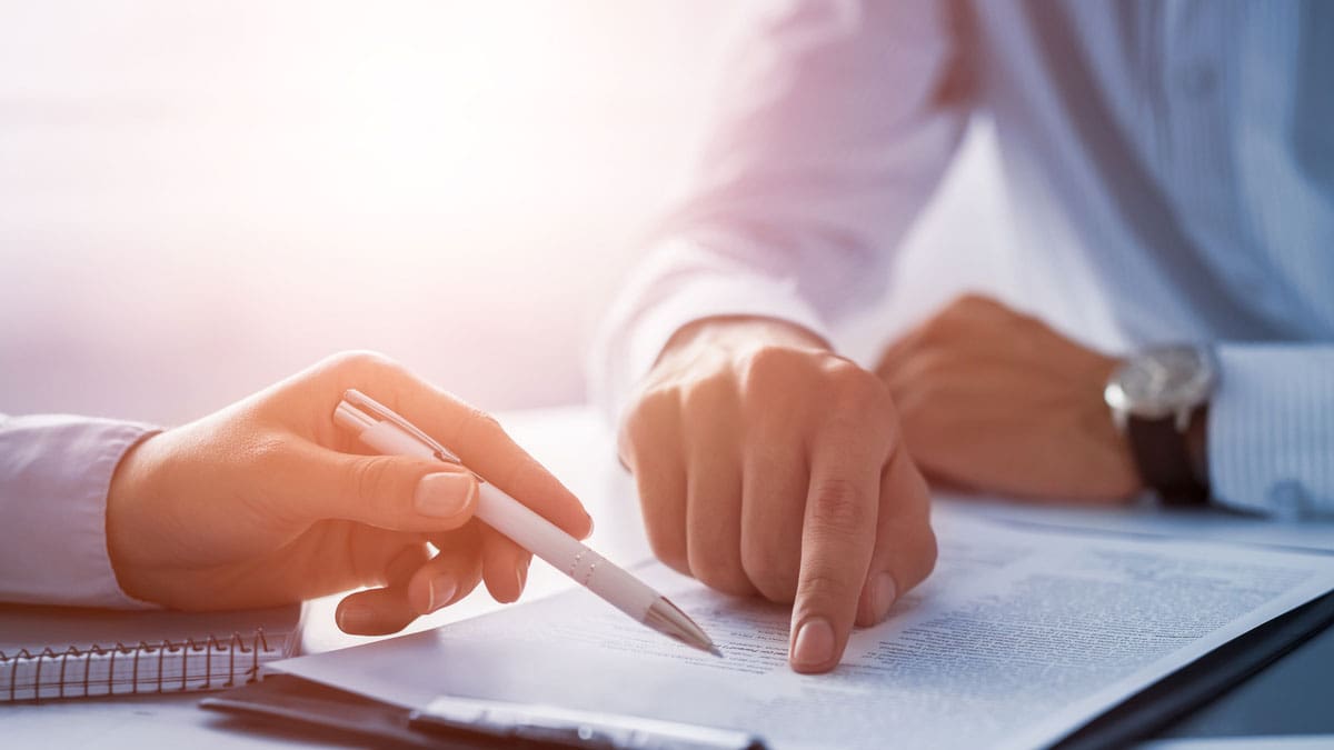 person-pointing-to-a-line-on-a-clipboard-while-another-signs