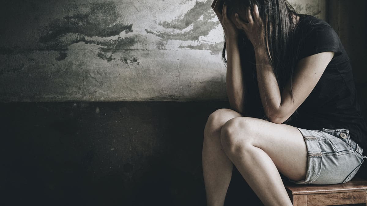 person-sitting-on-the-floor-against-a-wall-with-their-head-down