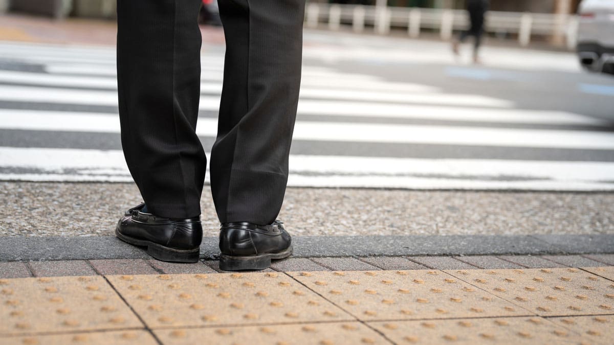 persons-feet-at-the-edge-of-a-curb-ramp-next-to-a-crosswalk