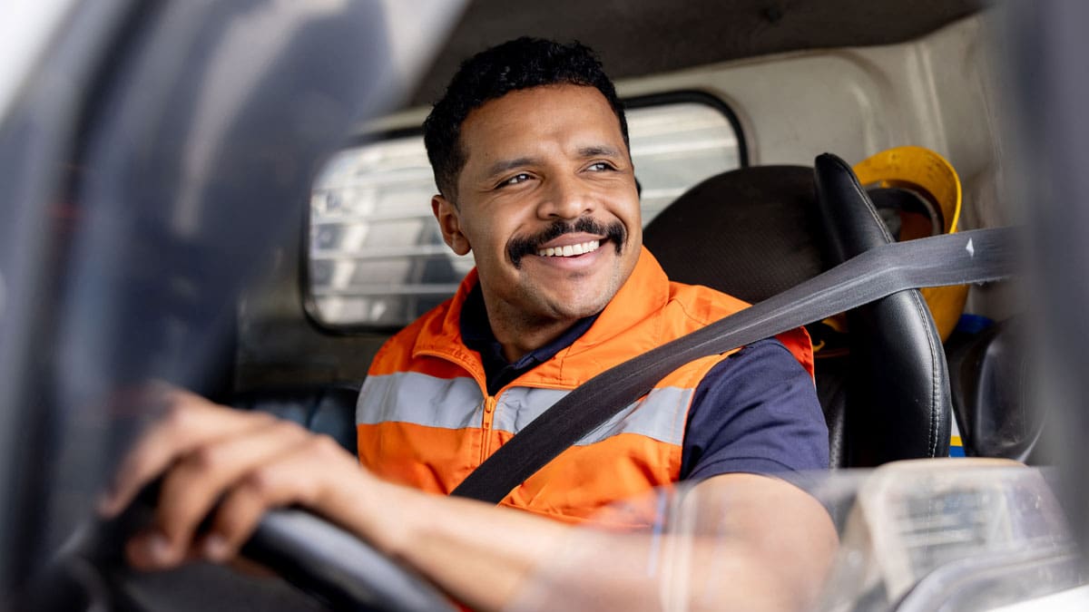 smiling-truck-driver-wearing-a-seat-belt-behind-the-wheel