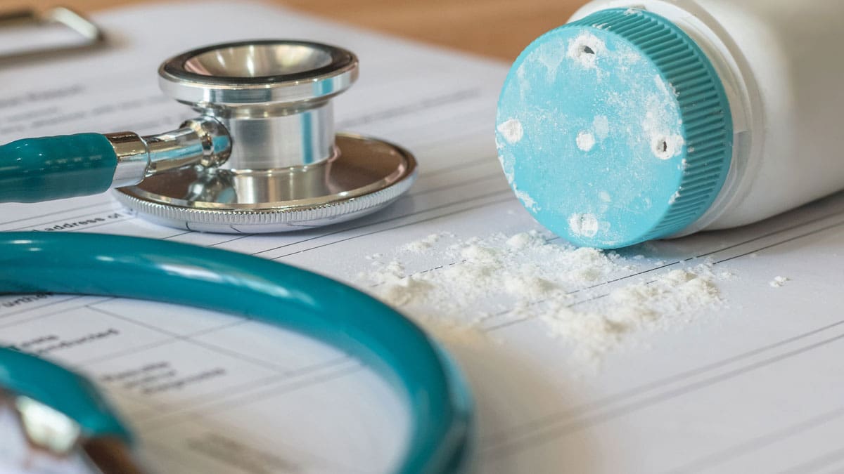 talcum-powder-bottle-spilled-on-a-desk-next-to-a-stethoscope-and-paperwork