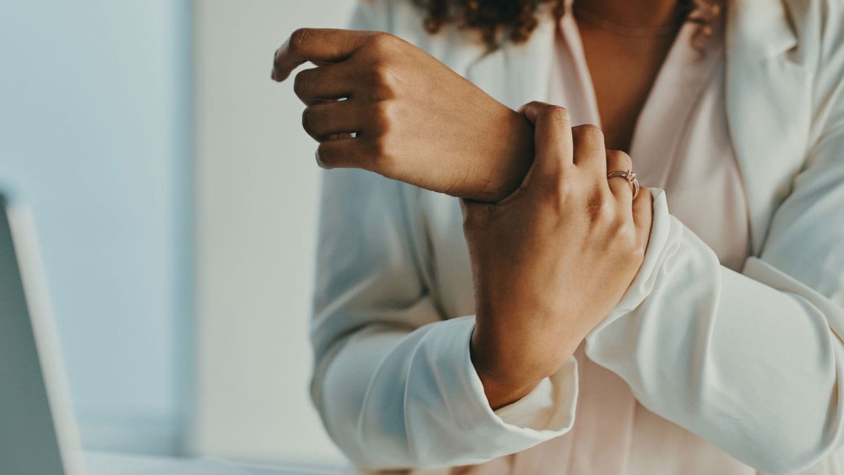 woman-holding-wrist-next-to-a-laptop