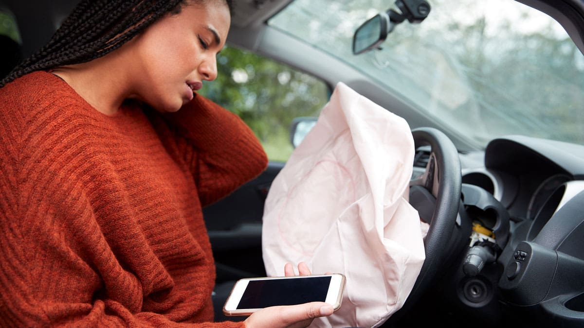 woman-on-her-phone-in-the-drivers-seat-with-the-airbag-deployed