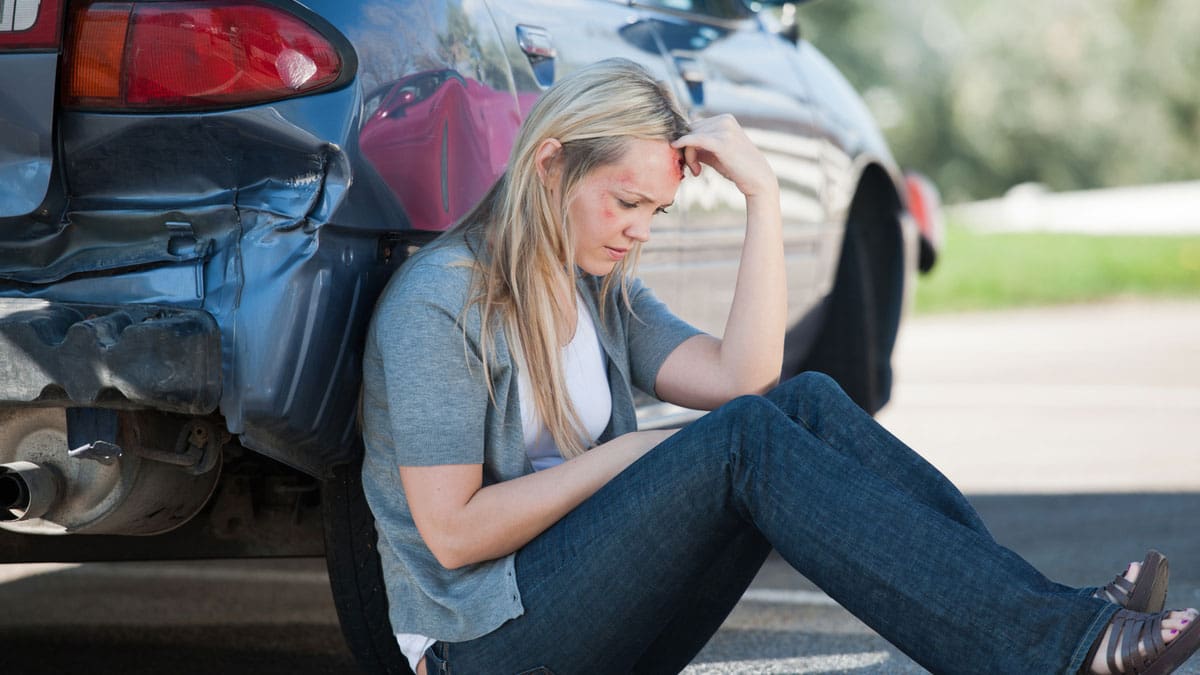 woman-sitting-on-the-ground-beside-a-damaged-car-after-a-collision