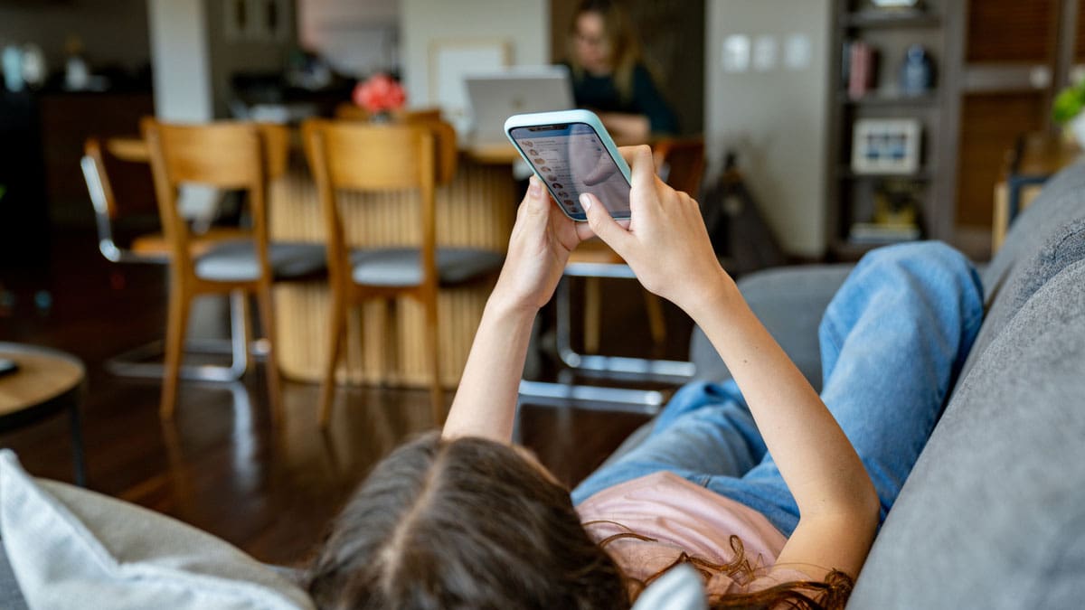 young-person-lying-on-back-on-a-couch-using-cell-phone