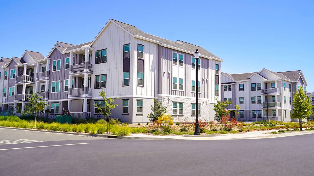 apartment-building-exterior-with-a-parking-area-and-lawn