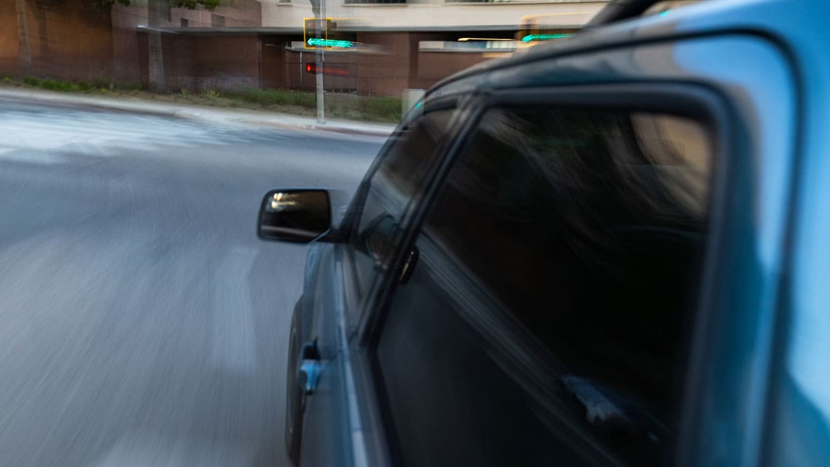 blue-car-with-a-turn-signal-lit-at-an-intersection