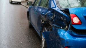 blue-car-with-rear-end-damage-stopped-in-traffic