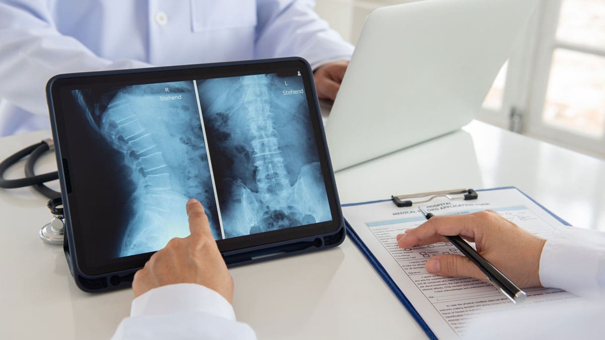 doctor-reviewing-an-x-ray-on-a-tablet-while-taking-notes