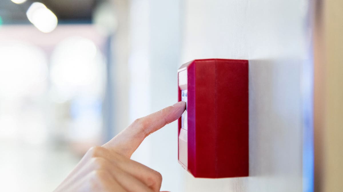 finger-pressing-a-red-emergency-call-button-on-a-wall