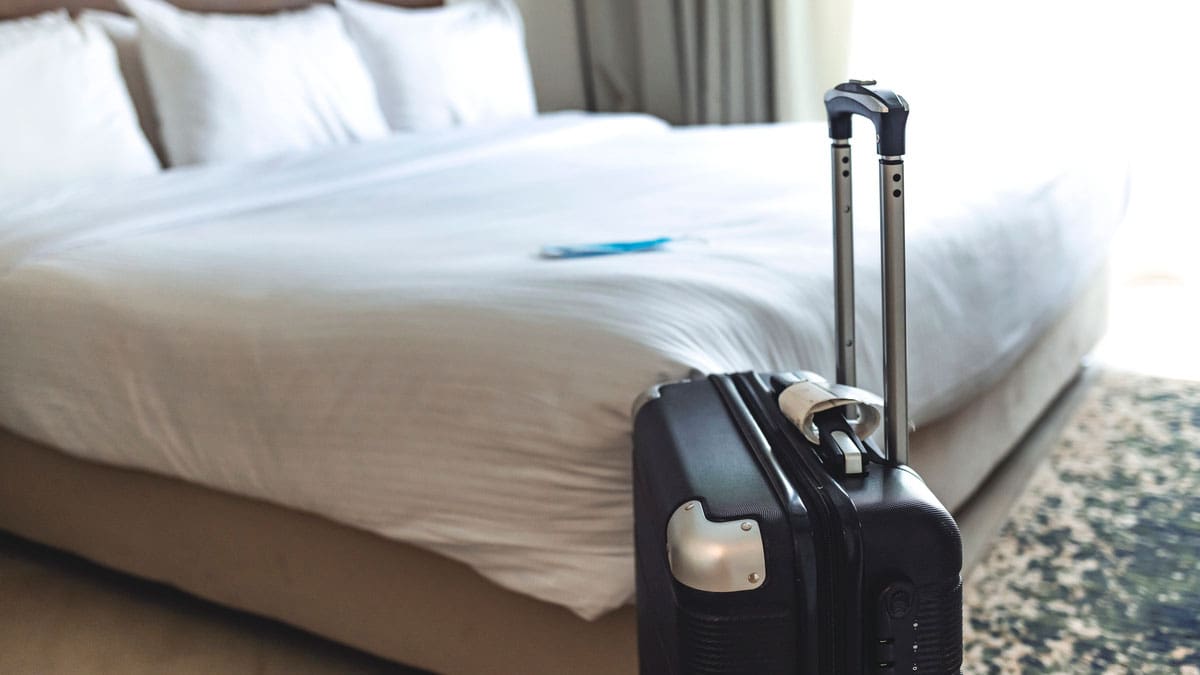 hotel-bed-with-a-suitcase-standing-beside-it