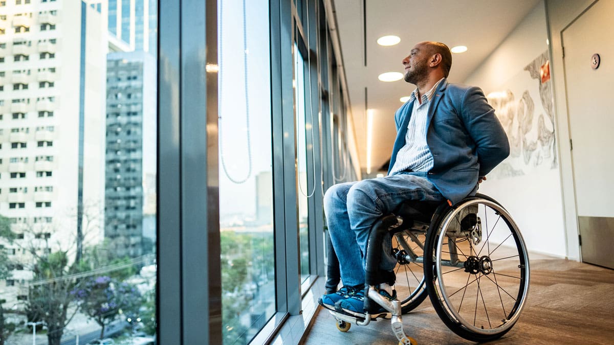 man-in-a-wheelchair-looking-out-a-window-at-the-city
